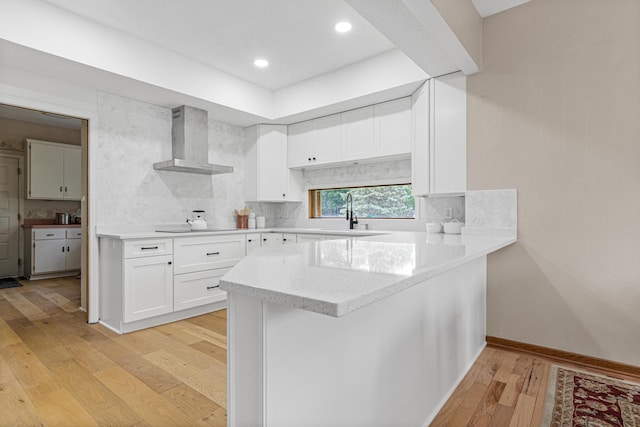 3817 Dunbar Ct N, Brooklyn Park, MN 55443 - kitchen with wall chimney exhaust hood, light wood finished floors, white cabinetry, a peninsula, and backsplash