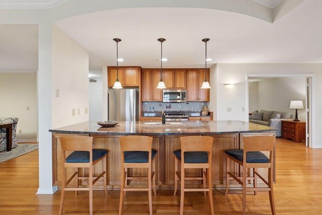 8301 Creekside Cir Unit 570, Bloomington, MN 55437 - kitchen with stainless steel appliances, light wood-style floors, decorative backsplash, dark stone countertops, and crown molding