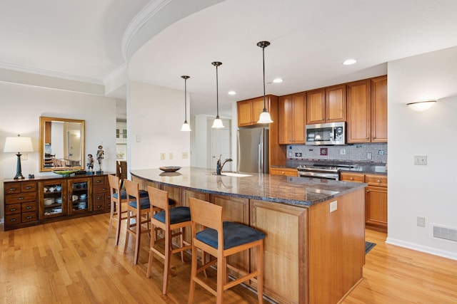 8301 Creekside Cir Unit 570, Bloomington, MN 55437 - kitchen with appliances with stainless steel finishes, light wood-type flooring, brown cabinetry, ornamental molding, and a breakfast bar