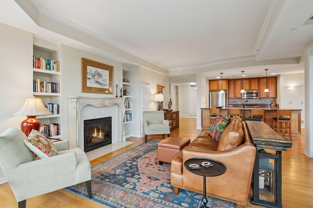 8301 Creekside Cir Unit 570, Bloomington, MN 55437 - living room featuring built in shelves, a fireplace with flush hearth, light wood-type flooring, and crown molding