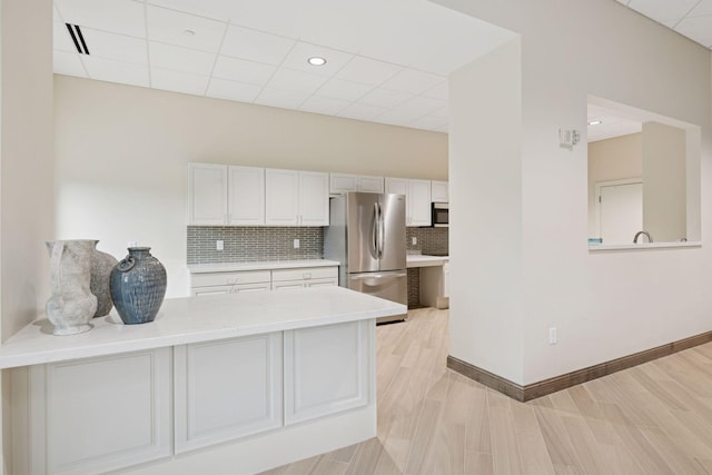 8301 Creekside Cir Unit 570, Bloomington, MN 55437 - kitchen with appliances with stainless steel finishes, light countertops, decorative backsplash, white cabinets, and light wood-style flooring