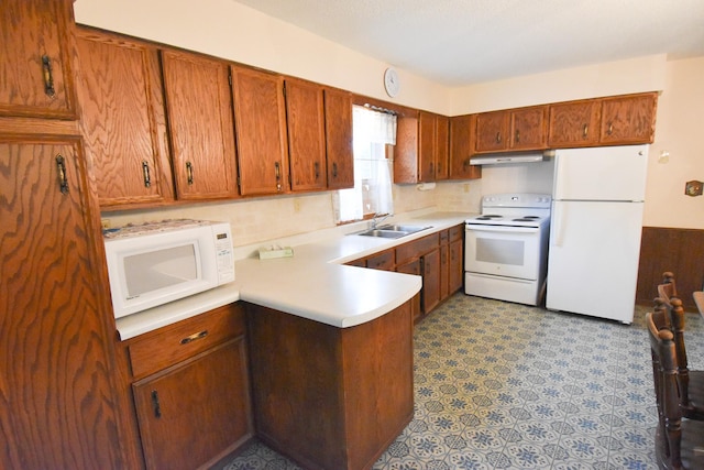 21840 320th Ave NW, Warren, MN 56762 - kitchen featuring white appliances, under cabinet range hood, brown cabinetry, a peninsula, and light countertops