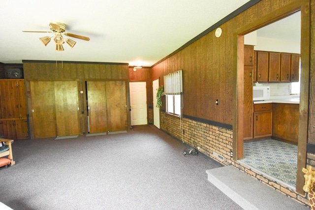 21840 320th Ave NW, Warren, MN 56762 - unfurnished living room featuring a ceiling fan, carpet flooring, wood walls, and crown molding