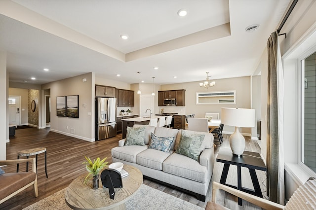1486 Otter Way, New Richmond, WI 54017 - living room featuring dark wood-style flooring, a chandelier, recessed lighting, and a tray ceiling