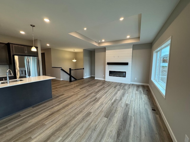 1486 Otter Way, New Richmond, WI 54017 - unfurnished living room featuring wood finished floors, a tray ceiling, recessed lighting, and a large fireplace