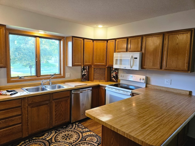 2705 9th St SW, Willmar, MN 56201 - kitchen with white appliances, a textured ceiling, a peninsula, brown cabinetry, and wooden counters