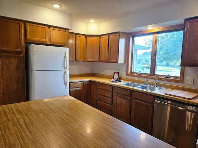 2705 9th St SW, Willmar, MN 56201 - kitchen with stainless steel dishwasher, freestanding refrigerator, light countertops, brown cabinets, and a textured ceiling