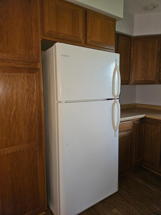 2705 9th St SW, Willmar, MN 56201 - kitchen with freestanding refrigerator, dark wood-style floors, brown cabinetry, and light countertops