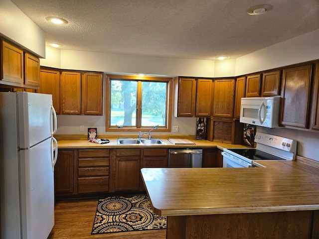 2705 9th St SW, Willmar, MN 56201 - kitchen with white appliances, a peninsula, a textured ceiling, dark wood-style floors, and light countertops