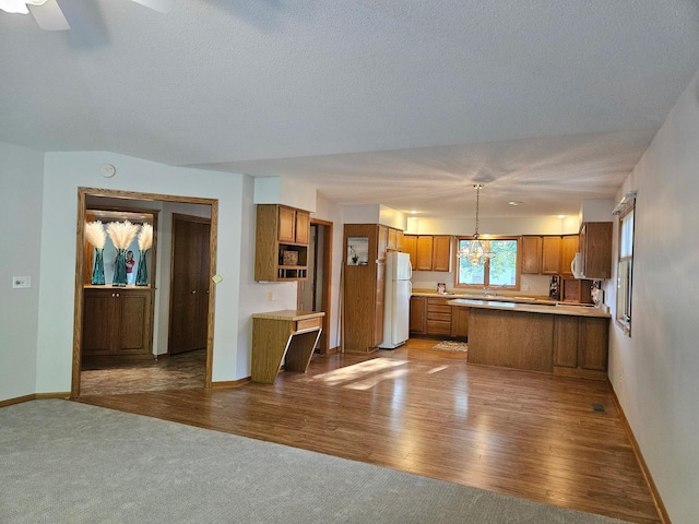 2705 9th St SW, Willmar, MN 56201 - kitchen with freestanding refrigerator, brown cabinets, a peninsula, open floor plan, and a textured ceiling
