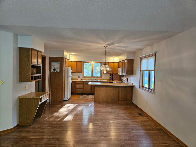 2705 9th St SW, Willmar, MN 56201 - kitchen with white appliances, brown cabinetry, a peninsula, dark wood-style flooring, and a textured ceiling