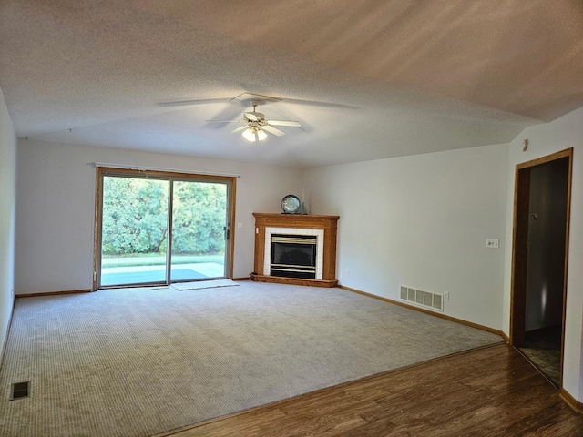 2705 9th St SW, Willmar, MN 56201 - unfurnished living room featuring ceiling fan, a tiled fireplace, wood finished floors, and a textured ceiling