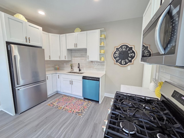 1323 Lincoln Ave, Saint Paul, MN 55105 - kitchen with stainless steel appliances, a sink, light countertops, white cabinetry, and light wood-type flooring