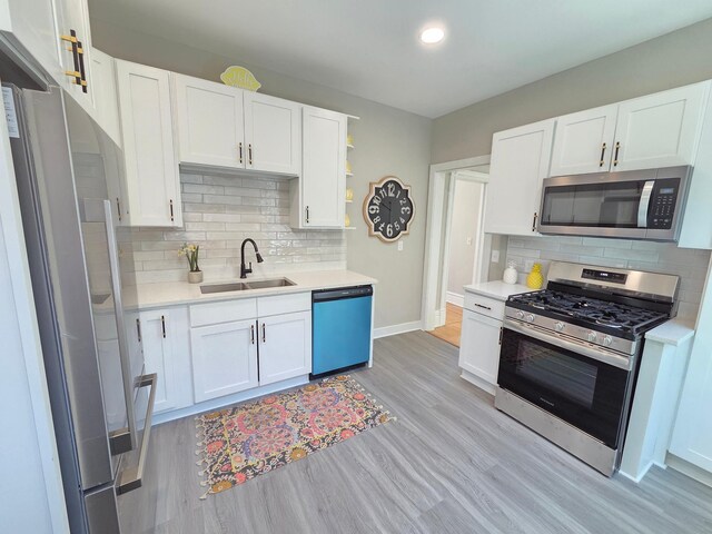 1323 Lincoln Ave, Saint Paul, MN 55105 - kitchen featuring appliances with stainless steel finishes, a sink, light countertops, light wood-style floors, and white cabinetry