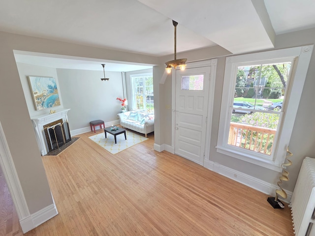 1323 Lincoln Ave, Saint Paul, MN 55105 - entrance foyer featuring light wood-style flooring, baseboards, radiator, and a fireplace with flush hearth