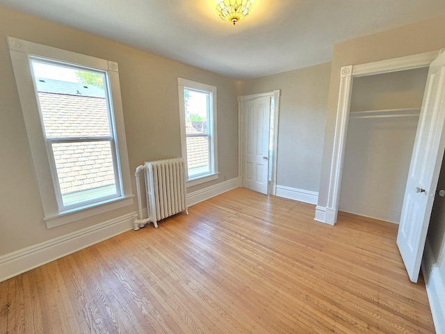 1323 Lincoln Ave, Saint Paul, MN 55105 - unfurnished bedroom with radiator heating unit, baseboards, light wood-type flooring, and a closet