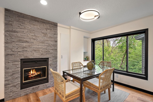 8335 Virginia Ave S, Bloomington, MN 55438 - dining room featuring a stone fireplace, light wood-style floors, and a textured ceiling