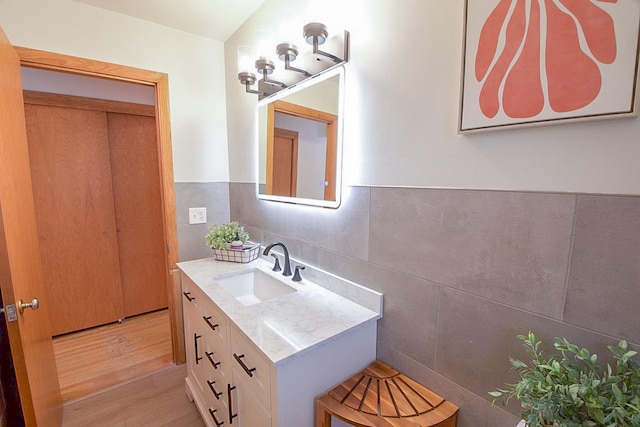 905 24th Ave N, Saint Cloud, MN 56303 - bathroom featuring vanity, wood finished floors, backsplash, and tile walls
