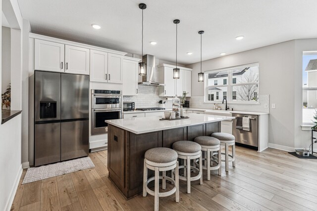 7872 Jade Ln, Victoria, MN 55386 - kitchen featuring stainless steel appliances, wall chimney exhaust hood, light wood-style floors, tasteful backsplash, and white cabinetry