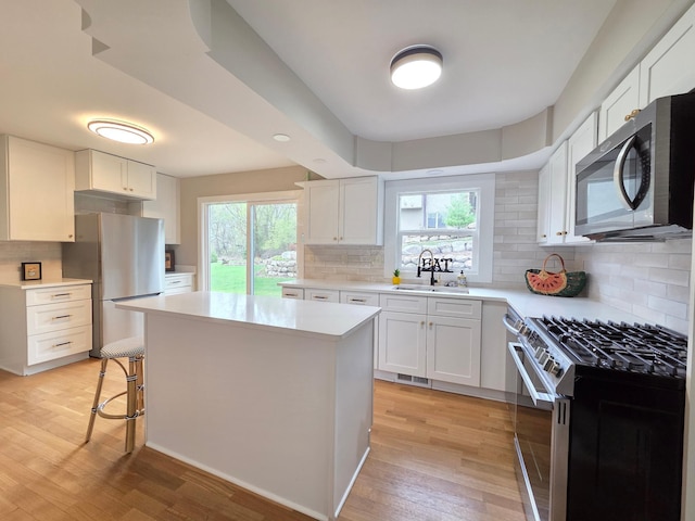 13801 Lake Street Ext, Minnetonka, MN 55345 - kitchen with appliances with stainless steel finishes, a sink, light wood-style floors, a kitchen island, and backsplash