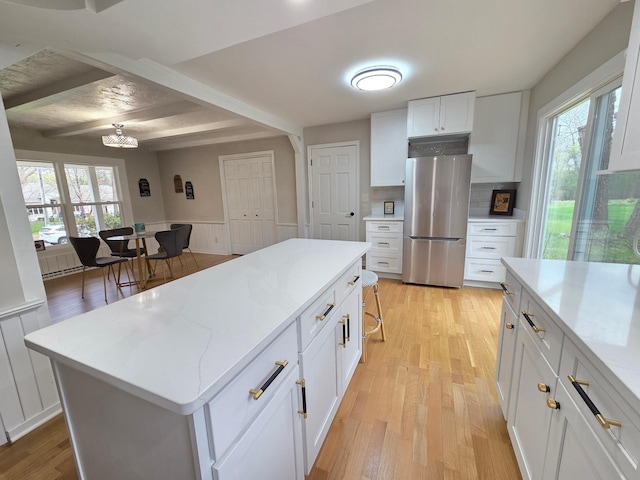 13801 Lake Street Ext, Minnetonka, MN 55345 - kitchen featuring freestanding refrigerator, white cabinetry, light wood-style flooring, a center island, and backsplash