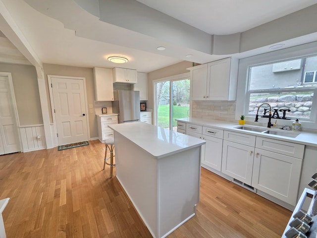 13801 Lake Street Ext, Minnetonka, MN 55345 - kitchen with freestanding refrigerator, a sink, light countertops, light wood finished floors, and white cabinets