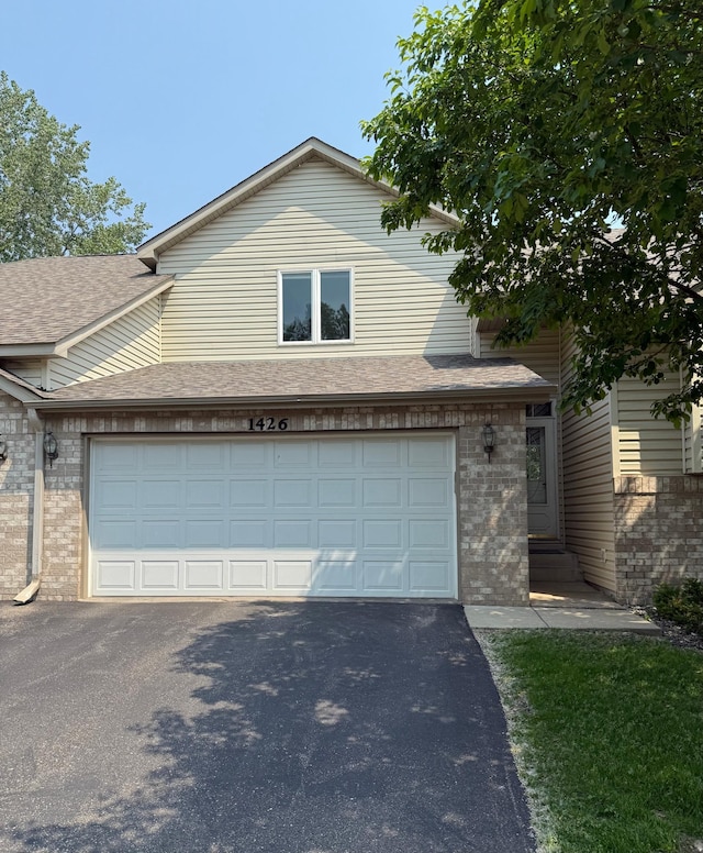 1426 Mcandrews Rd E Unit 30, Burnsville, MN 55337 - view of front of property with brick siding, asphalt driveway, a garage, a shingled roof, and entry steps