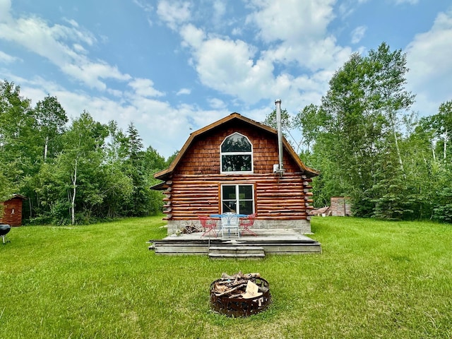 3274 County Road 1 SW, Boone Twp, MN 56623 - back of house with log siding, a lawn, an outdoor fire pit, and a deck