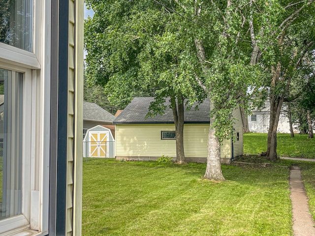 4241 Tyler St NE, Columbia Heights, MN 55421 - view of property exterior featuring a lawn, a storage unit, and a shingled roof