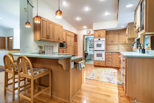 28647 State Highway 78, Otter Tail Twp, MN 56515 - kitchen featuring stainless steel microwave, a peninsula, white double oven, light wood-style floors, and a kitchen bar