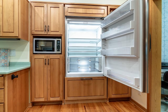 28647 State Highway 78, Otter Tail Twp, MN 56515 - kitchen with stainless steel microwave, light wood-style floors, light countertops, and brown cabinetry