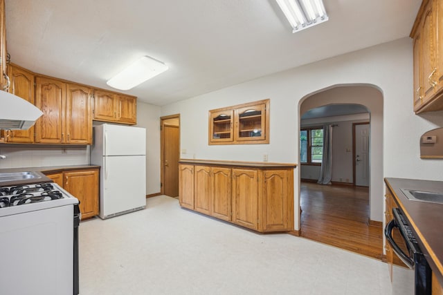 16584 River Rd, Green Prairie Twp, MN 56345 - kitchen with white appliances, arched walkways, light flooring, exhaust hood, and brown cabinetry