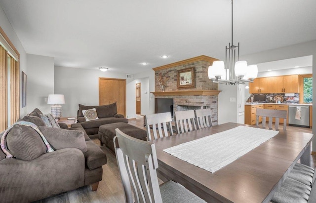 2434 Southcrest Ave E, Maplewood, MN 55119 - dining area featuring light wood finished floors, a chandelier, a brick fireplace, and recessed lighting