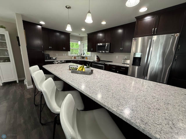 409 1st Ave E, Ada, MN 56510 - kitchen featuring appliances with stainless steel finishes, light stone counters, a kitchen bar, decorative light fixtures, and recessed lighting