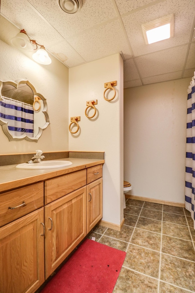 2607 Forest View Dr NE, Bemidji, MN 56601 - full bath featuring vanity, a drop ceiling, toilet, tile patterned floors, and baseboards