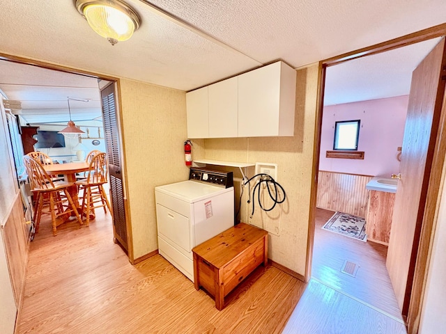 2683 22nd St NW Lot 8, Baudette, MN 56623 - laundry area featuring washer / dryer, light wood-style flooring, cabinet space, and a textured ceiling