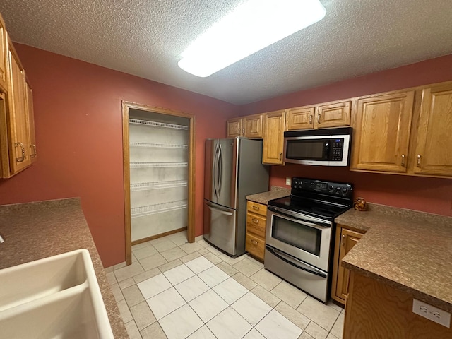 3211 30th Ave S, Fargo, ND 58103 - kitchen featuring stainless steel appliances, dark countertops, a textured ceiling, and light tile patterned flooring