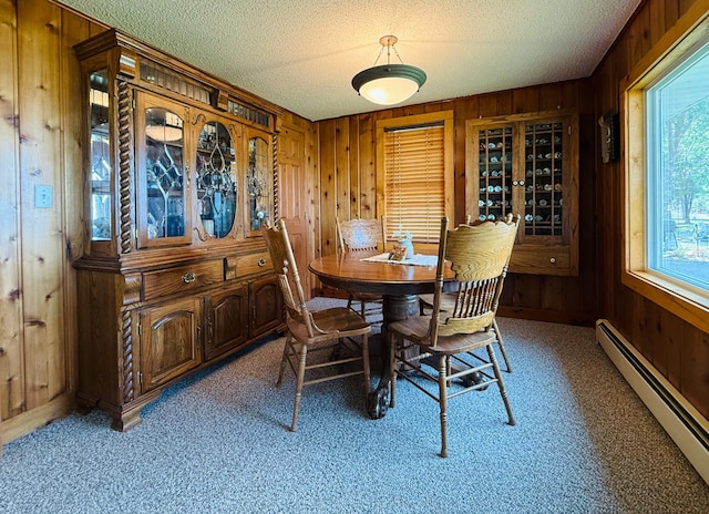 15127 Twilight Rd, Kathio Twp, MN 56359 - dining area with baseboard heating, wooden walls, a textured ceiling, and light carpet