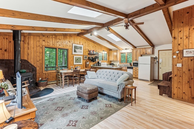 2225 Antler Lake Ct, Milltown, WI 54858 - living area with a wood stove, a ceiling fan, a skylight, light wood-style floors, and wooden walls