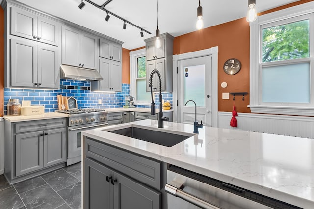 737 5th St E, Saint Paul, MN 55106 - kitchen with gray cabinetry, appliances with stainless steel finishes, under cabinet range hood, dark marble finish flooring, and wainscoting