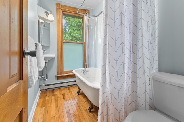 737 5th St E, Saint Paul, MN 55106 - bathroom with baseboard heating, hardwood / wood-style floors, a freestanding tub, and a shower with curtain