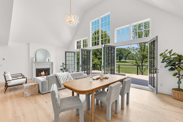 4603 Merilane Ave, Edina, MN 55436 - dining area with high vaulted ceiling, a warm lit fireplace, light wood-style floors, and a chandelier