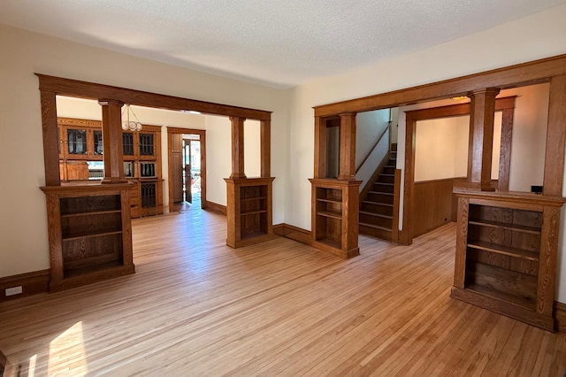 3140 Fremont Ave S, Minneapolis, MN 55408 - unfurnished room with light wood-style floors, stairway, a textured ceiling, and decorative columns