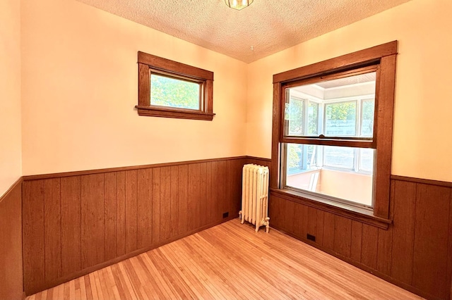 3140 Fremont Ave S, Minneapolis, MN 55408 - unfurnished room with radiator, wainscoting, wood-type flooring, a textured ceiling, and wood walls