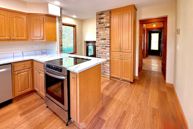 3140 Fremont Ave S, Minneapolis, MN 55408 - kitchen featuring stainless steel appliances, a peninsula, light wood finished floors, a textured ceiling, and light stone countertops