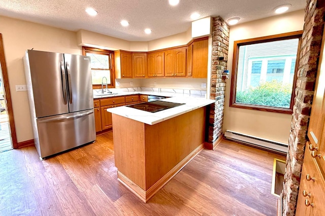 3140 Fremont Ave S, Minneapolis, MN 55408 - kitchen with appliances with stainless steel finishes, a peninsula, a baseboard radiator, light wood finished floors, and brown cabinetry