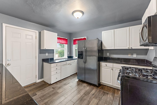 984 Iglehart Ave, Saint Paul, MN 55104 - kitchen with appliances with stainless steel finishes, dark wood-type flooring, white cabinets, dark stone countertops, and a textured ceiling