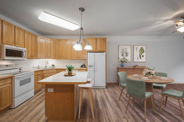 9165 Comstock Ln N Unit 106, Maple Grove, MN 55311 - kitchen with white appliances, wood finished floors, a center island, light countertops, and decorative light fixtures