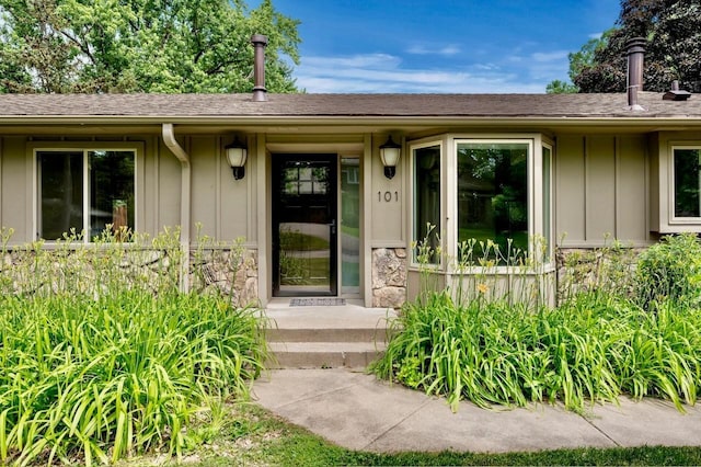 101 Sunset Dr S, Minnetonka, MN 55305 - doorway to property with board and batten siding, stone siding, and a shingled roof