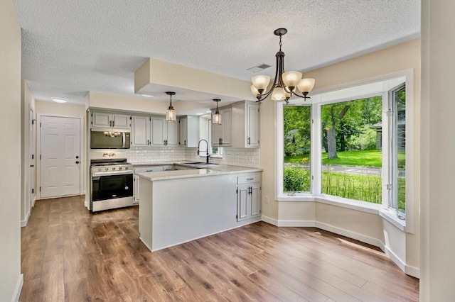 101 Sunset Dr S, Minnetonka, MN 55305 - kitchen featuring appliances with stainless steel finishes, a peninsula, light countertops, a textured ceiling, and wood finished floors